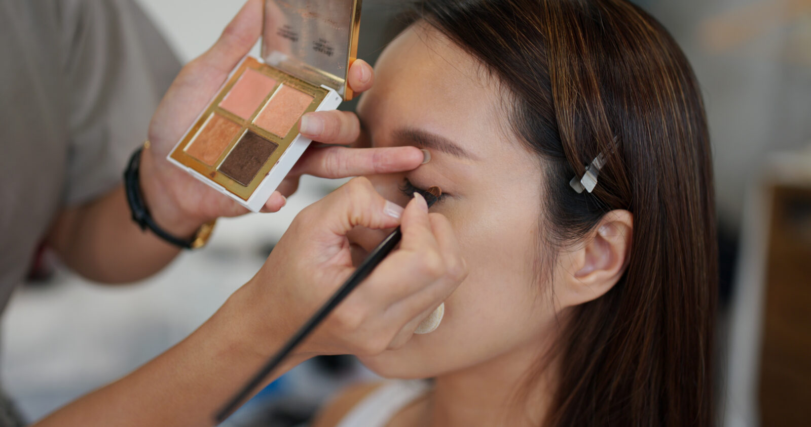 Maquilladora maquilla a una modelo femenina en el estudio