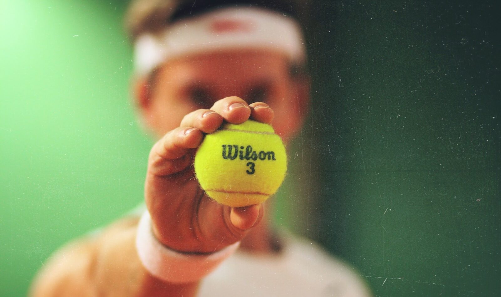 person holding green Wilson tennis ball