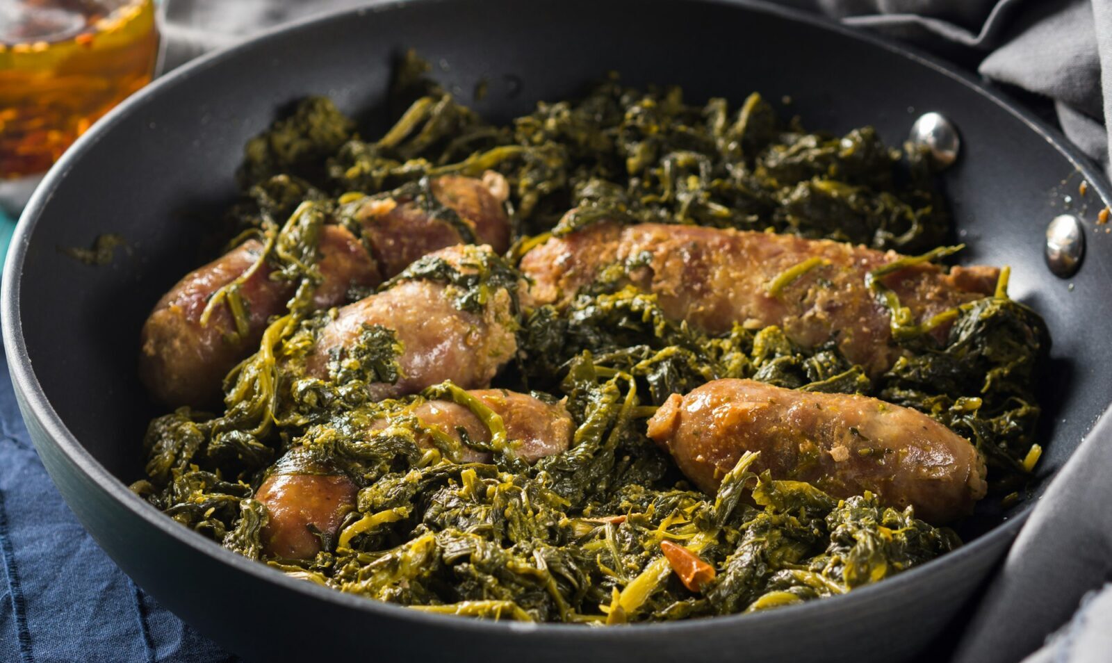 Salchichas italianas con brócoli rapini en una sartén