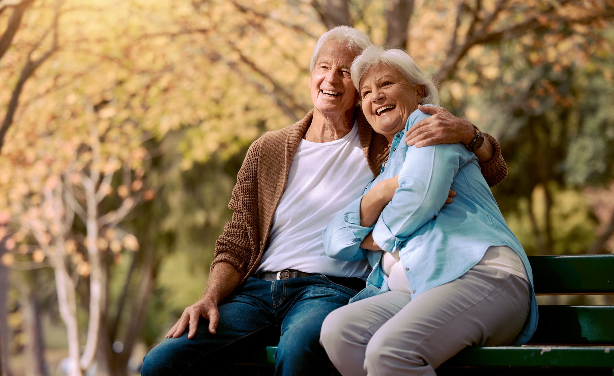 Senior couple, park bench and happy while sitting together in retirement for freedom, peace and cal