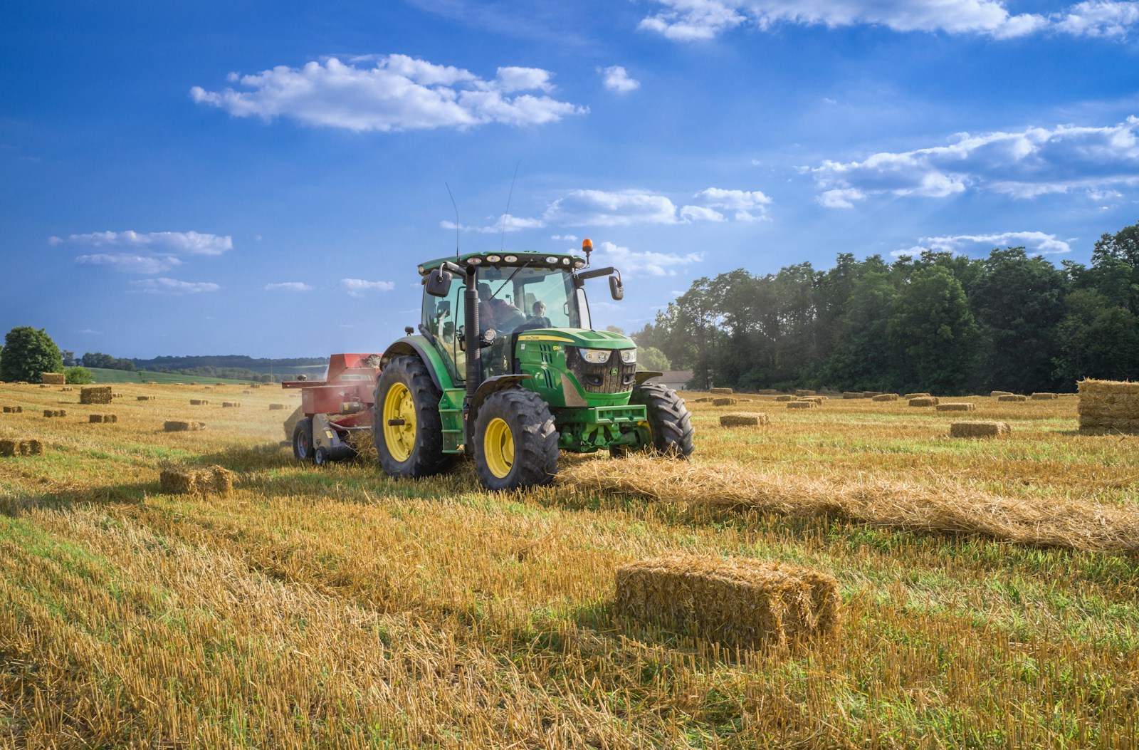 Grüner Traktor auf braunem Rasenfeld unter blauem Himmel tagsüber