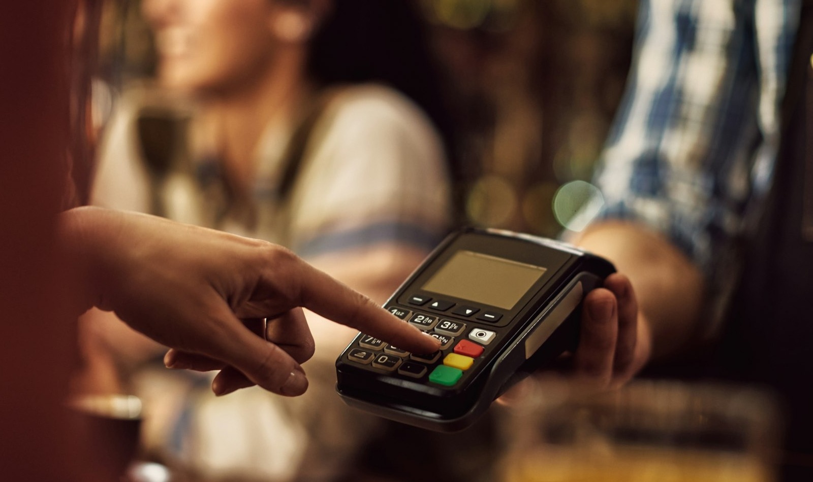 Primer plano de una mujer escribiendo pin mientras realiza el pago en una cafetería.